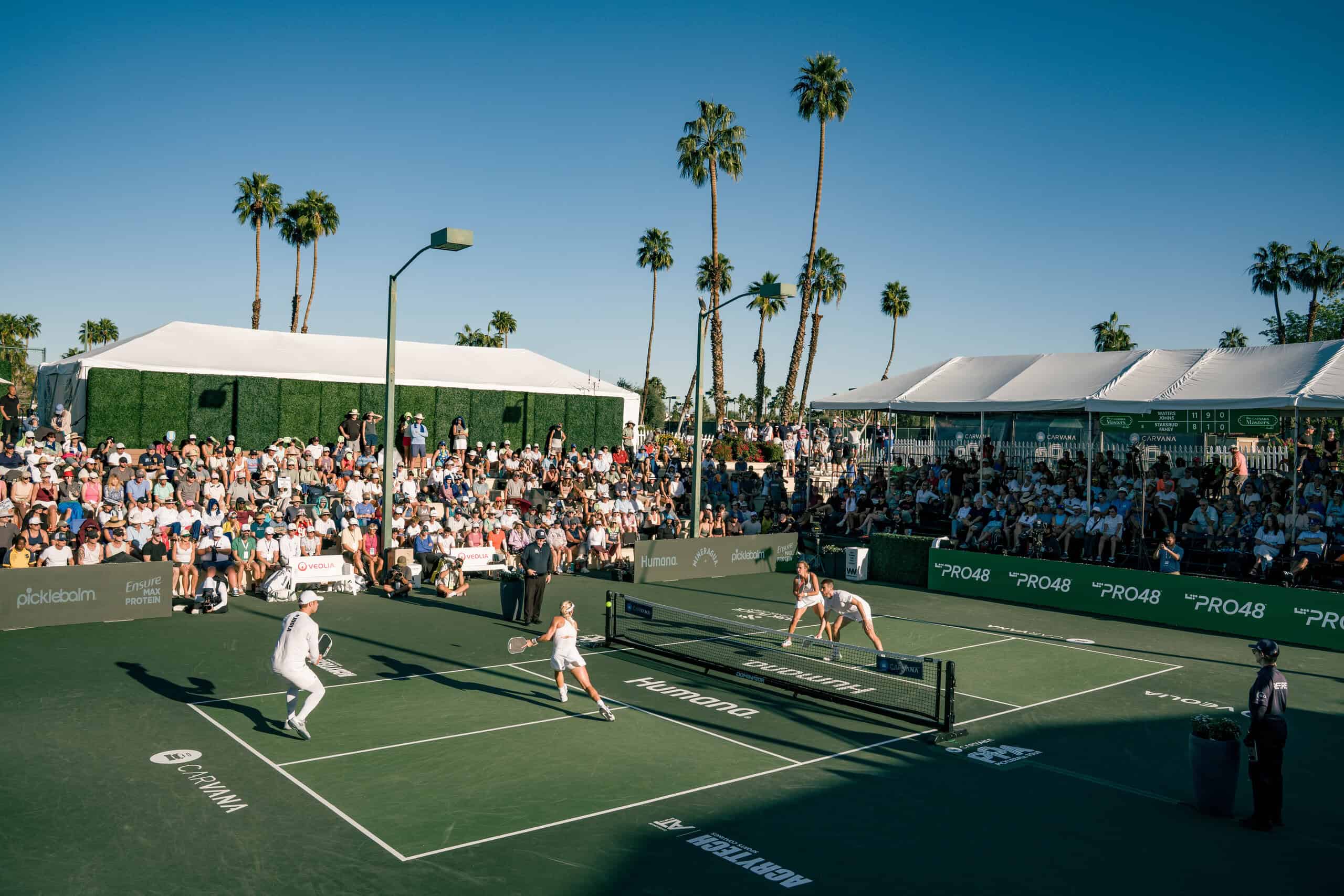 Pickleball match at PPA Tour event with players and spectators under sunny skies.
